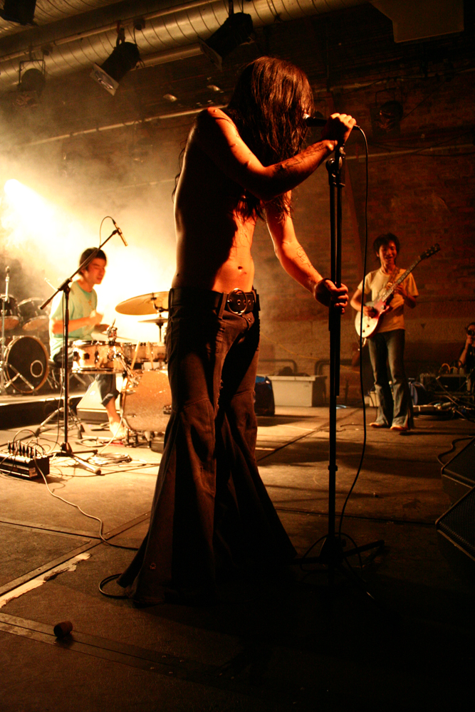 drummer left, singer in foreground and guitarist behind to the right 