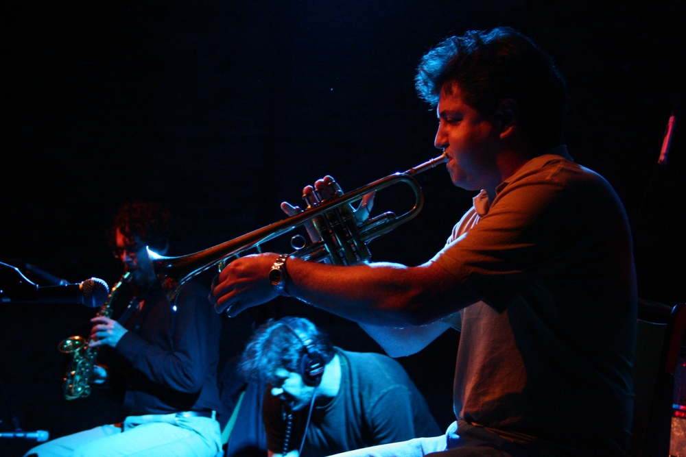 Close up of Greg Kelley playing a trumpet, Bhob and Jason in the background