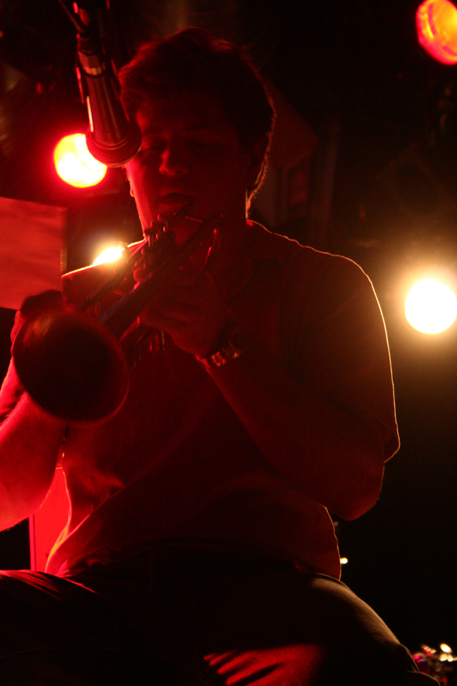 Greg Kelley about to play a trumpet, lit from behind