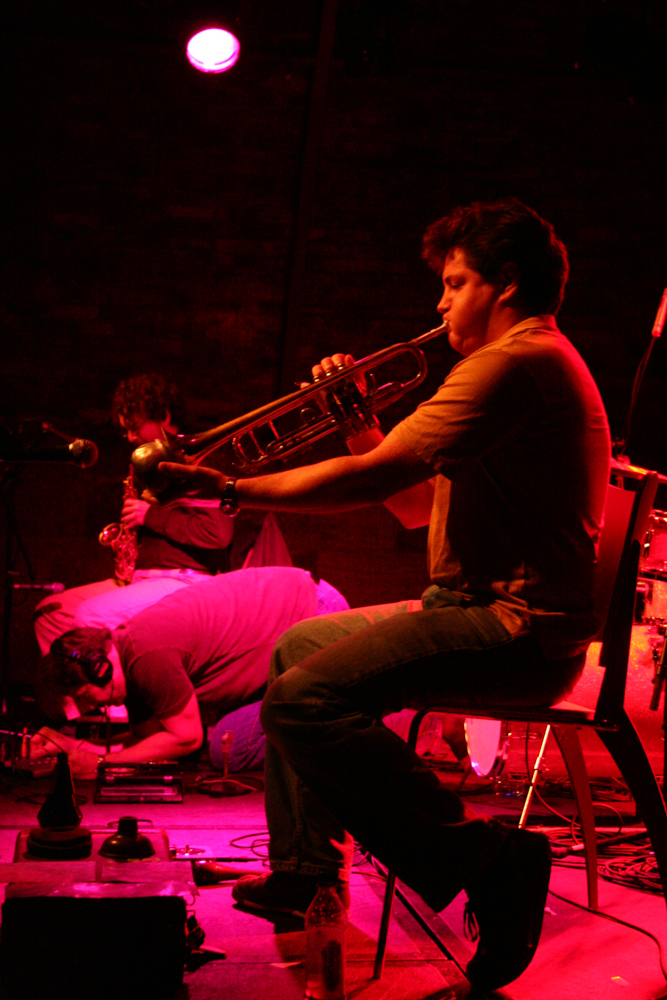 Greg Kelley holding a mute to the trumpet, jason on the floor, greg with sax