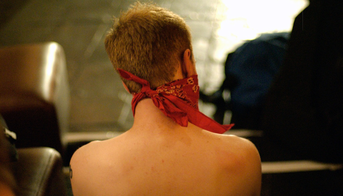 A view of Kylie Minoise's bare back with a red bandand tied around their head