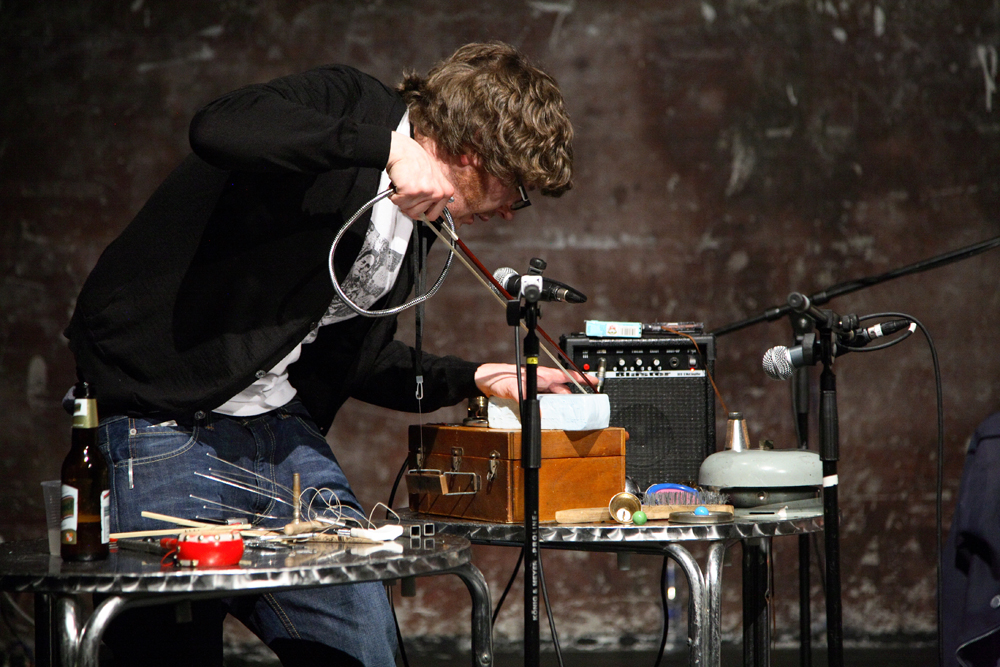 Ali Robertson Hunches over a table with lots of small metal objects on it 