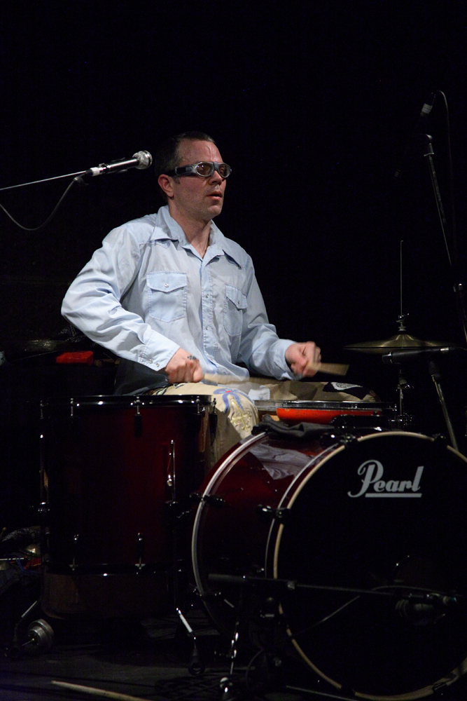 Fritz Welch plays a red drum kit whilst grimacing