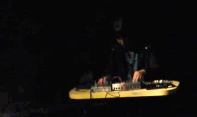 in a dark room Karen Constance plays a mixer on a yellow table