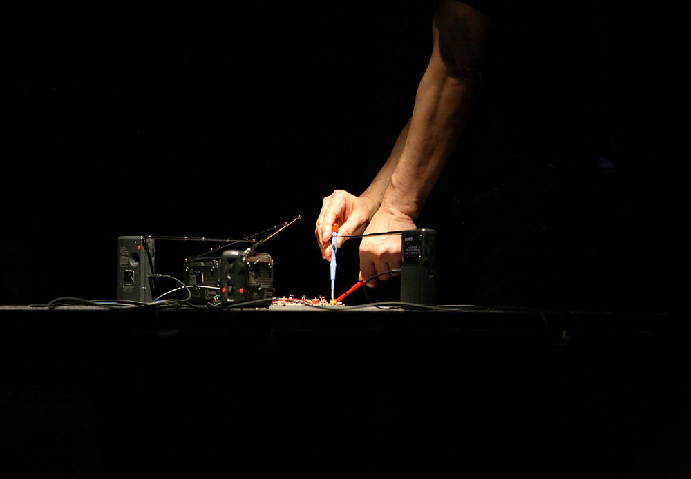 Tetsuo Kogawa solders a circuit live inside a circle of radios
