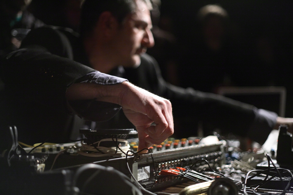 Jerome Noetinger's hand twiddling a knob on a mixing desk is in the foreground