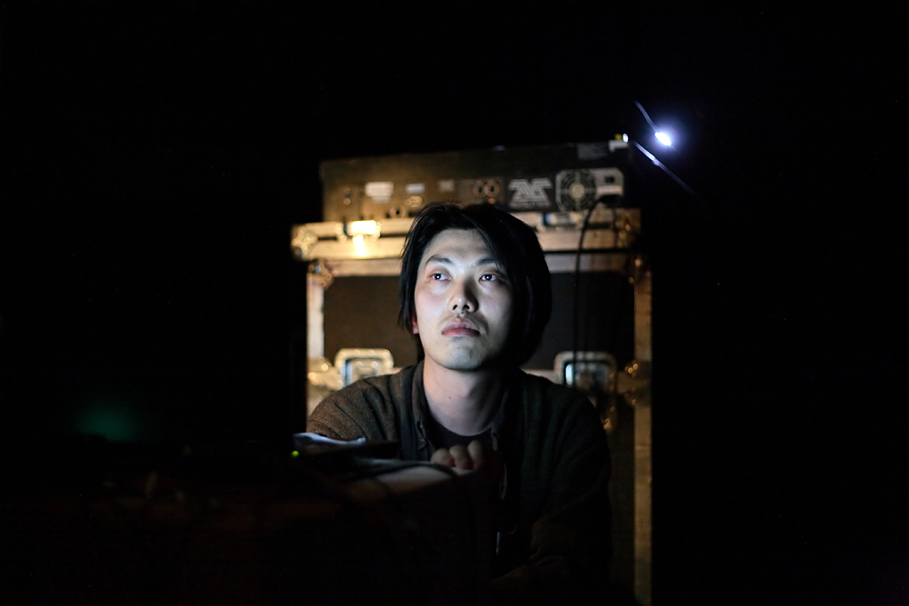 Taku Unami looks moodily at a computer screen darkness all around