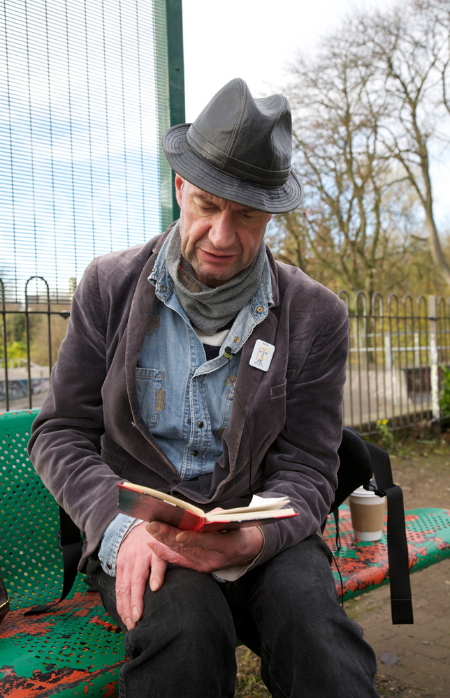 Tam Dean Burn reading on a bench somewhere in Glasgow