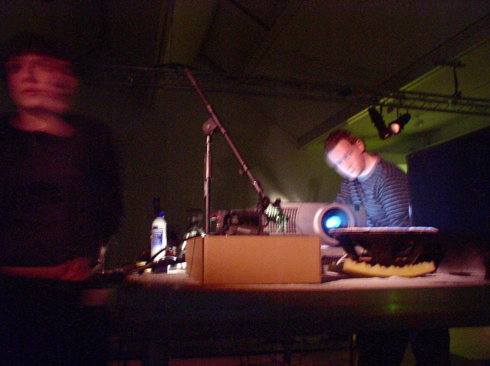 A blurred image of two people working with projection equipment