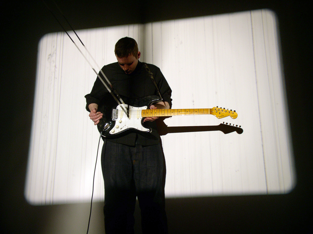 A man holding a guitar with a strip of film in the strings