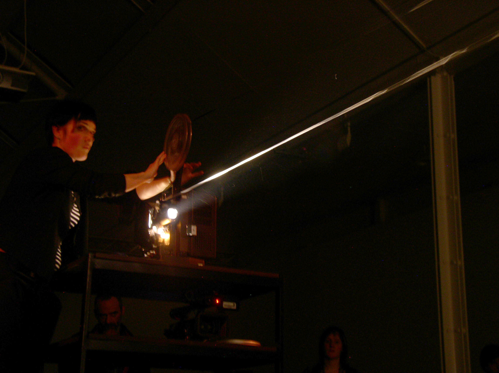 Emma Hart and film loop lit from the glare of a projector