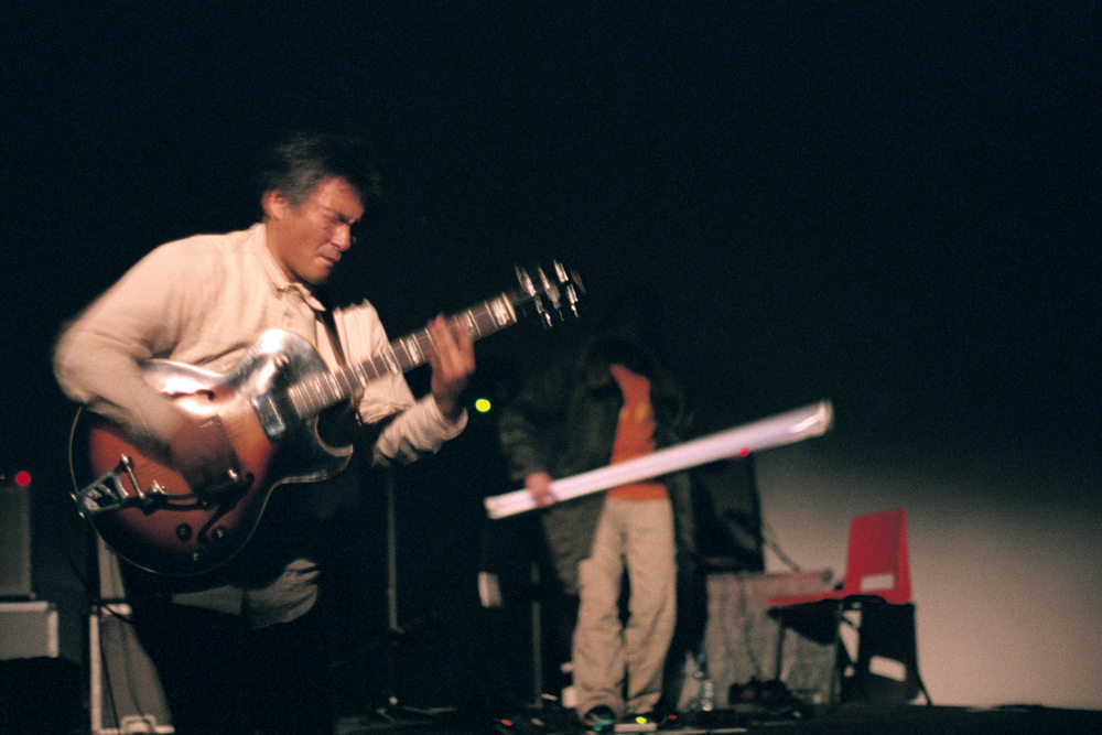 Kazuo Imai and Astuhiro Ito on stage with guitar and light bulb