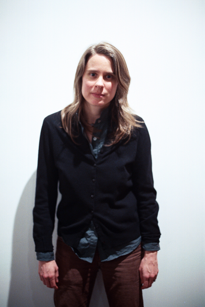 Portrait of Jennifer Reeves against a white background, arms dangling