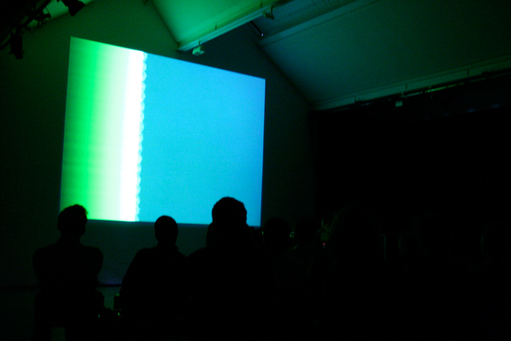Projection of a distorted signal in blues and greens on a wall