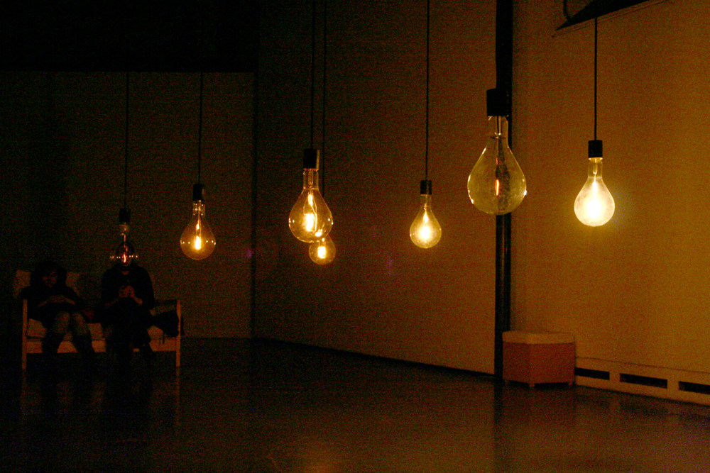 A series of large dimly lit light bulbs hanging in a room