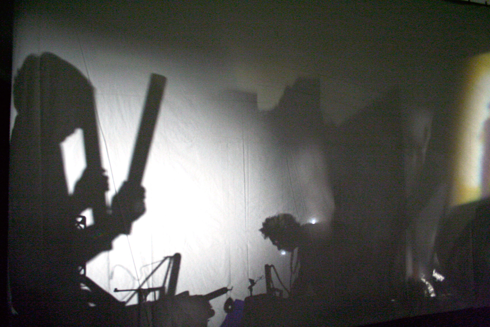 silhouettes of musicians behind a screen