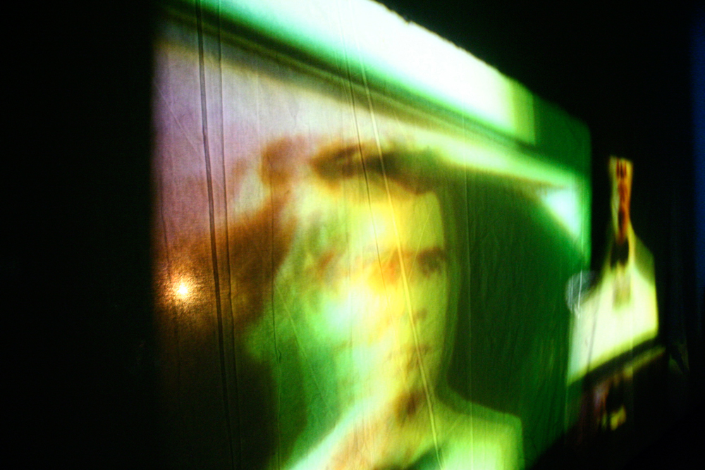 A distorted projection of a face and other images showing on a screen