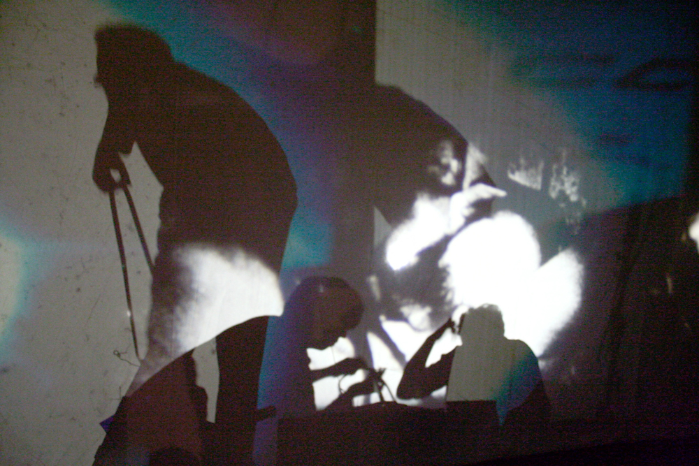 Figures moving around behind a screen lit from within by projectors