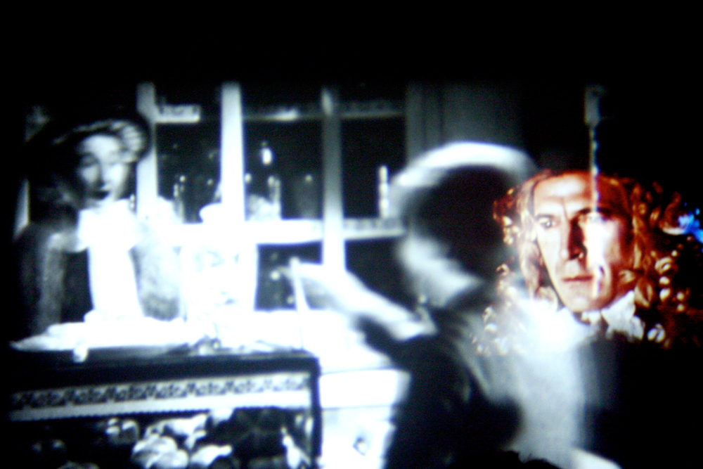 Layers of projection on a screen, a man's face with wig to the right