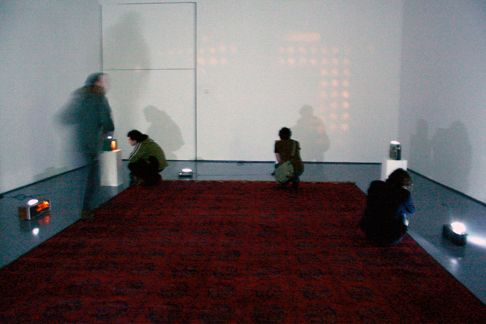 A room full of radios with fluorescent tube lights, a red rug on the floor