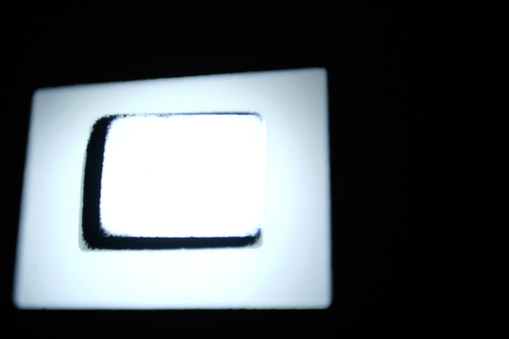 Two rectangular forms of white light against black on a screen