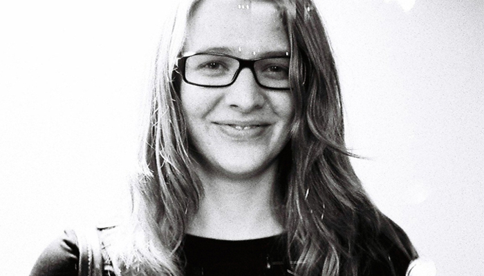 Heather Leigh Murray with glasses and long hair smiles at the camera