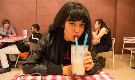 Jackie Wang drinking through a straw in a cafe