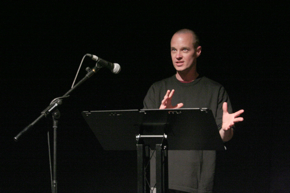 Craig Dworkin standing by a microphone giving a talk