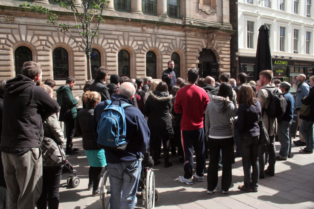 A group of people huddle round a speaker in George Square, Glasgow