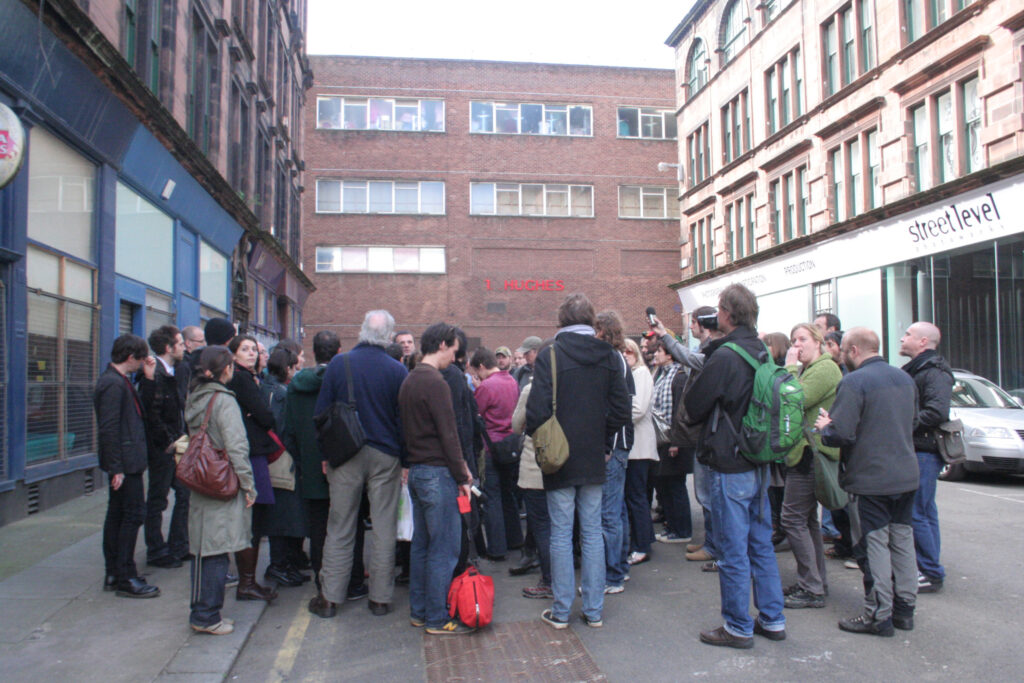 People standing in a huddle on a street in Glasgow's Merchant City