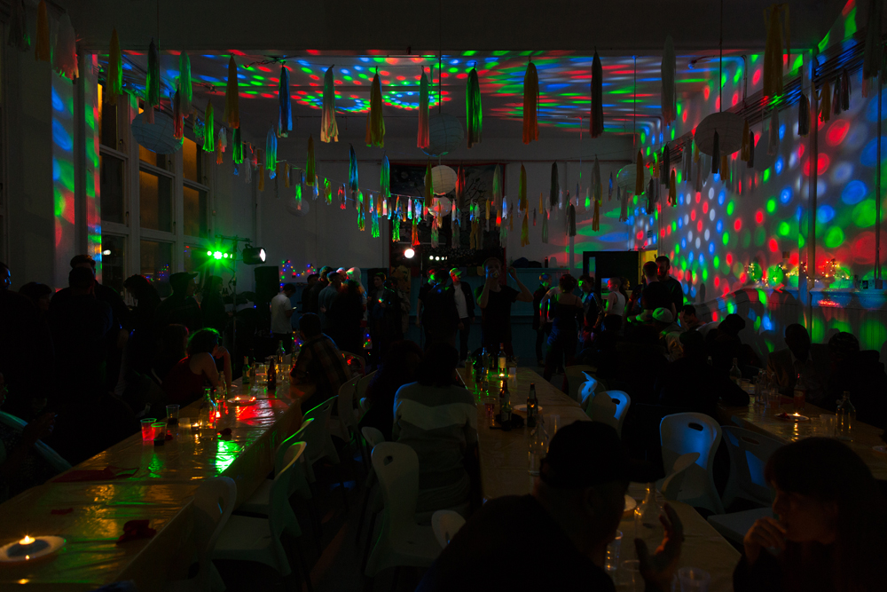 Coloured lights refracted around a dark space with people barely visible