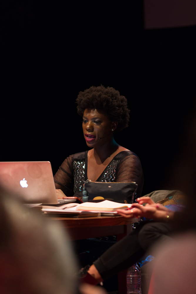a woman reading from a laptop on a stage 