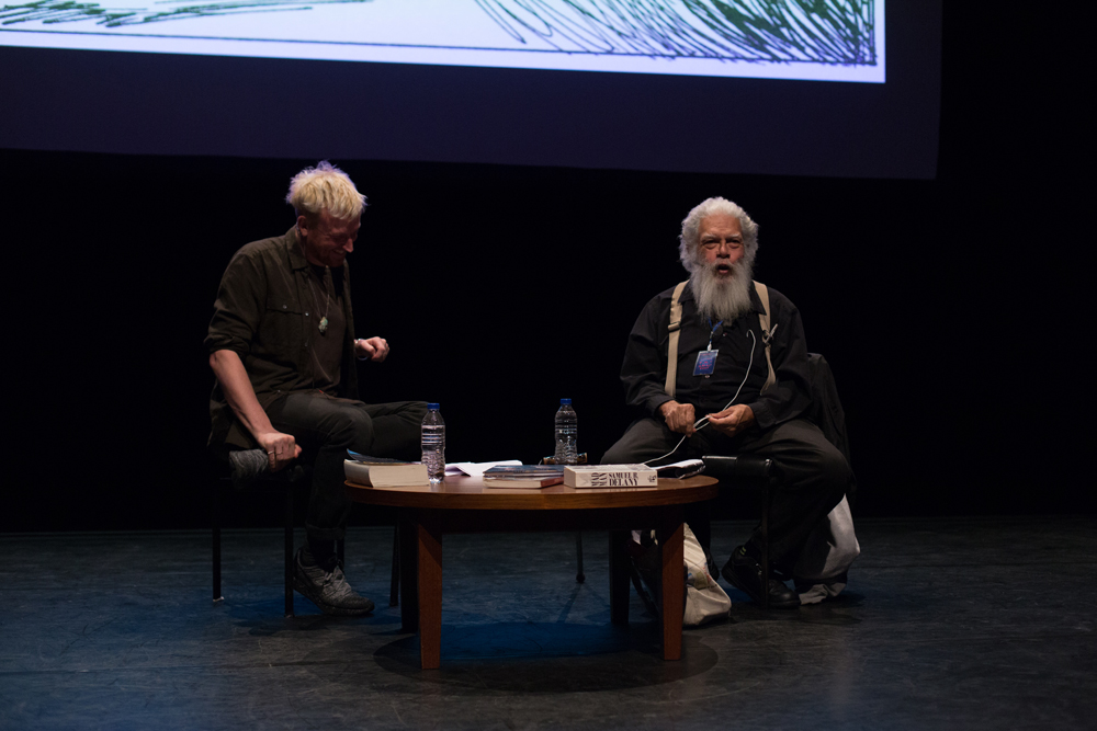 Barry Esson and Samuel Delany on stage by a small table with a screen behind