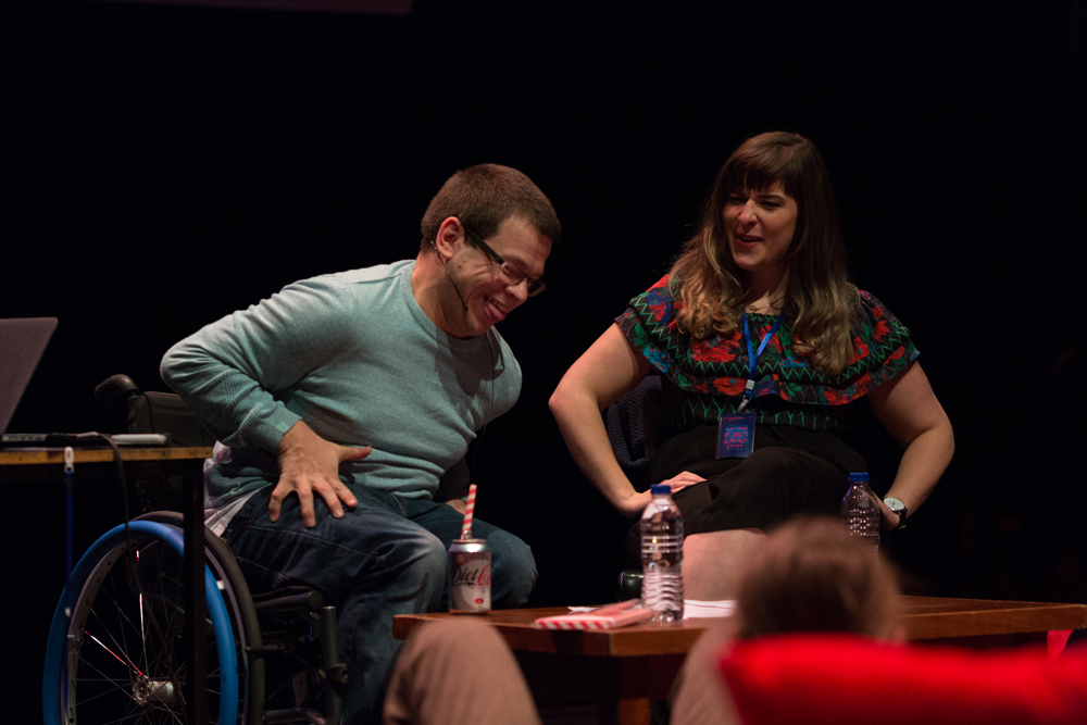 Two people laughing one in a blue jumper and the other in a patterned shirt