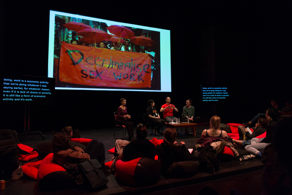 Projection of a poster, a discussion, audience, red cushions in a theatre