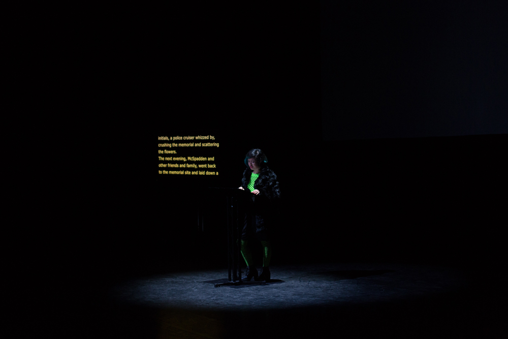 Jackie Wang reading from a lectern in front of a screen