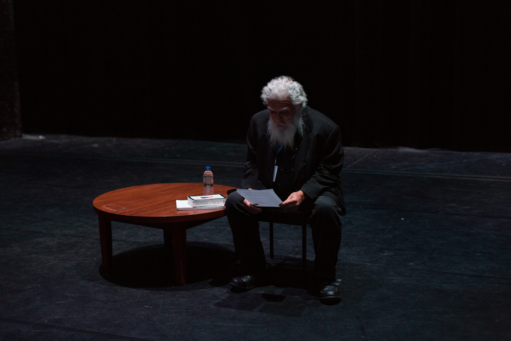 Samuel Delany reading from a document on stage; bearded with grey hair 