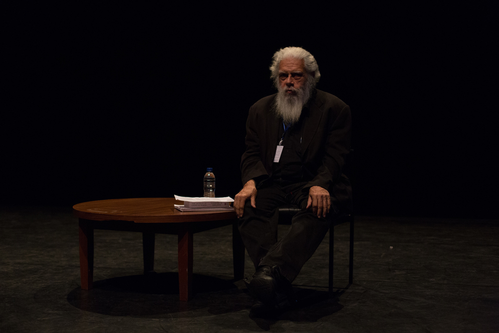 Samuel Delany seated next to a small table with a book and papers