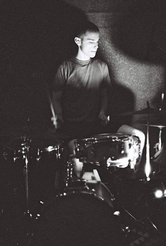 Chris Corsano angelic behind a drum kit cymbal shadows on either side