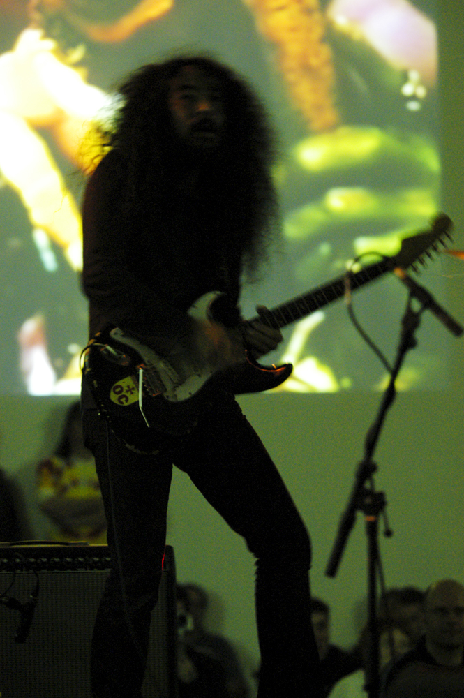 Makoto Kawabata playing electric guitar in front of a projection 