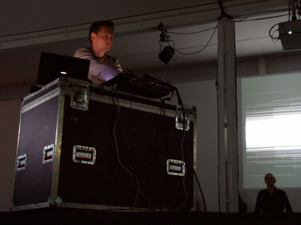 Carsten Nicolai operating some equipment near a projection
