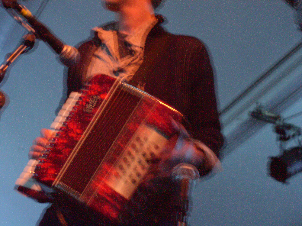 Someone holding an accordion near microphones