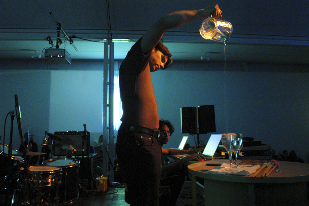a man pouring water from a jug into a vessel during a performance at KYTN 03