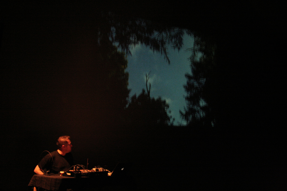 Lee Patterson sitting next to a projection of trees