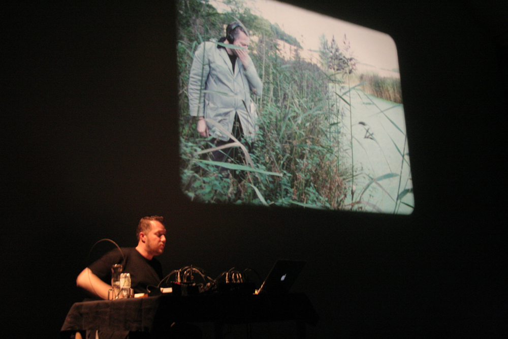 Lee Patterson sitting next to a projection of himself, pensive