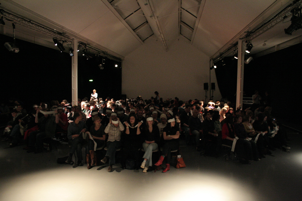 An audience seated and wearing eye masks