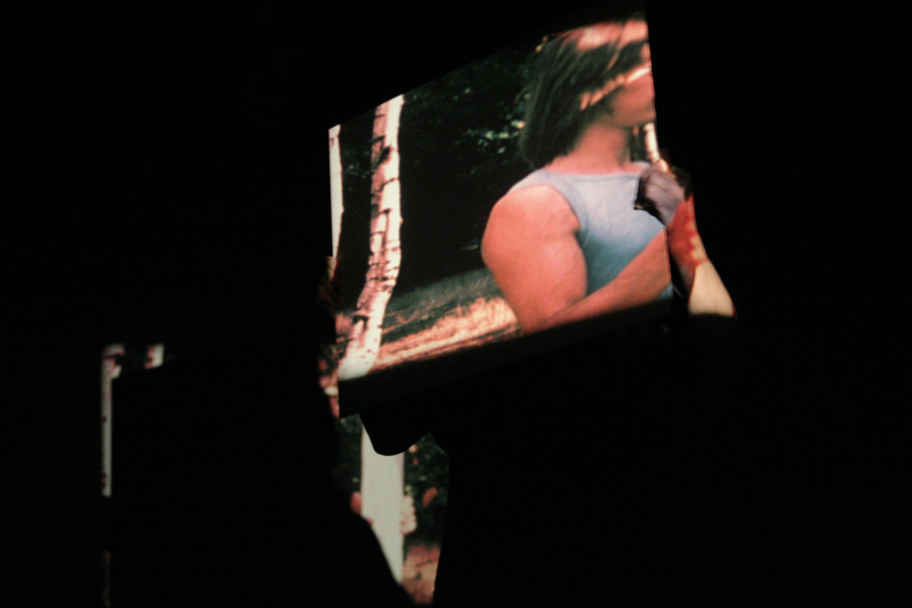 Guy sherwin holding a mirror showing a projection of himself with another mirror