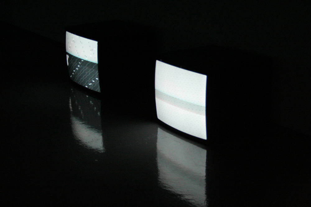 Two tv monitors  in a gallery showing patterns of dots