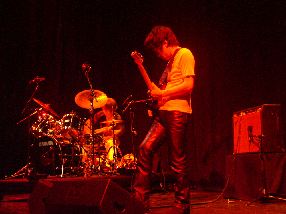 Kyoaku No Intention on stage playing drums and guitar in orange light at MLFC 05