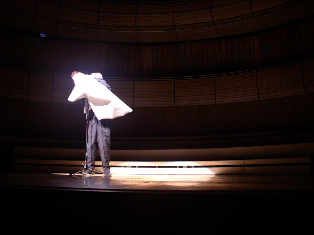 Takehisa Kosugo wraps a sheet of paper around a microphone